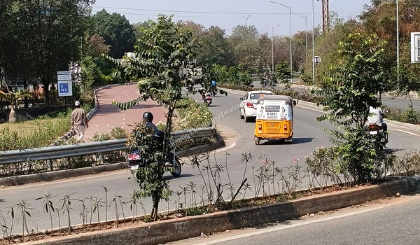 March 03 , 2026 - A view of the well-maintained curved access route with daily commuter traffic passing by the landscaped medians near the Prestige Kollur Hyderabad development zone and Nehru Outer Ring Road.