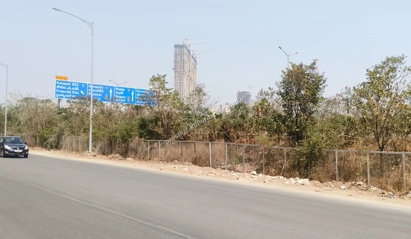 Large blue highway directional boards indicating routes to major IT hubs, visible from the Prestige Kollur Hyderabad site boundaries near the Nehru Outer Ring Road, captured on March 03 , 2026.