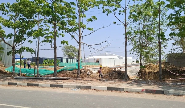 Temporary site walkway setup with green netting and a blue tent at the Prestige Kollur property in Kollur, Hyderabad